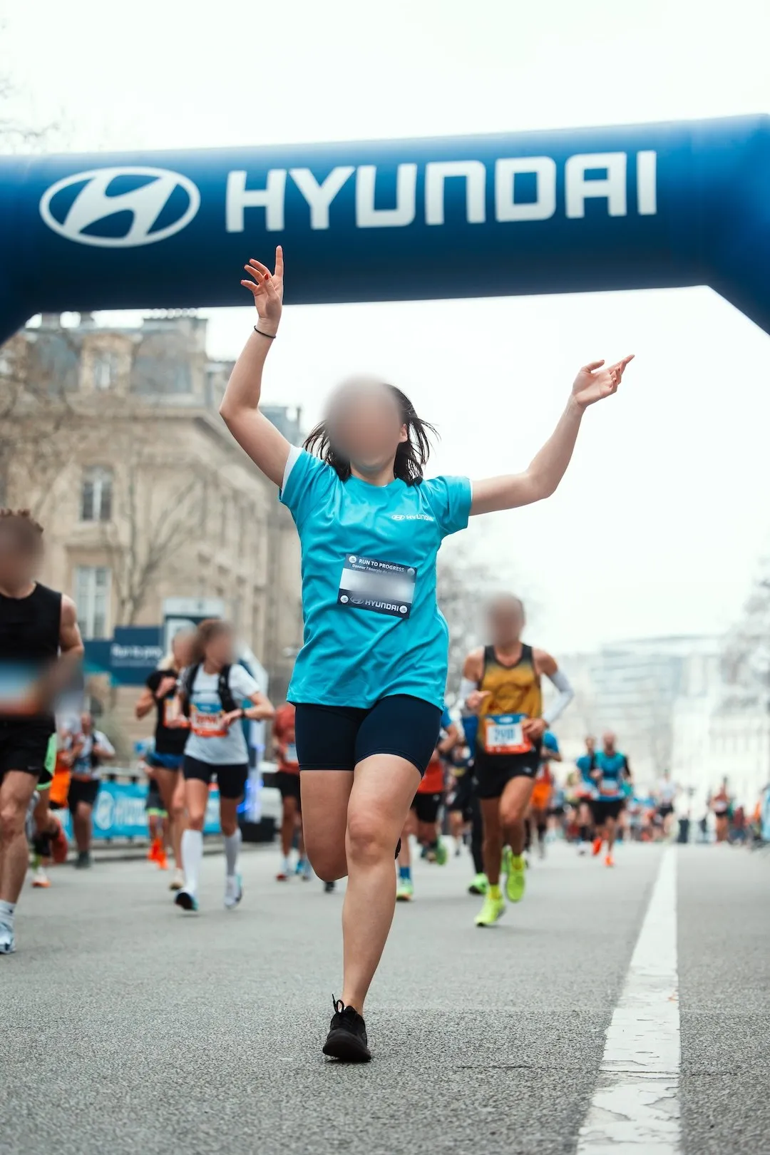 Une coureuse passe les bras levés sous l'arche Hyundai Run to Progress