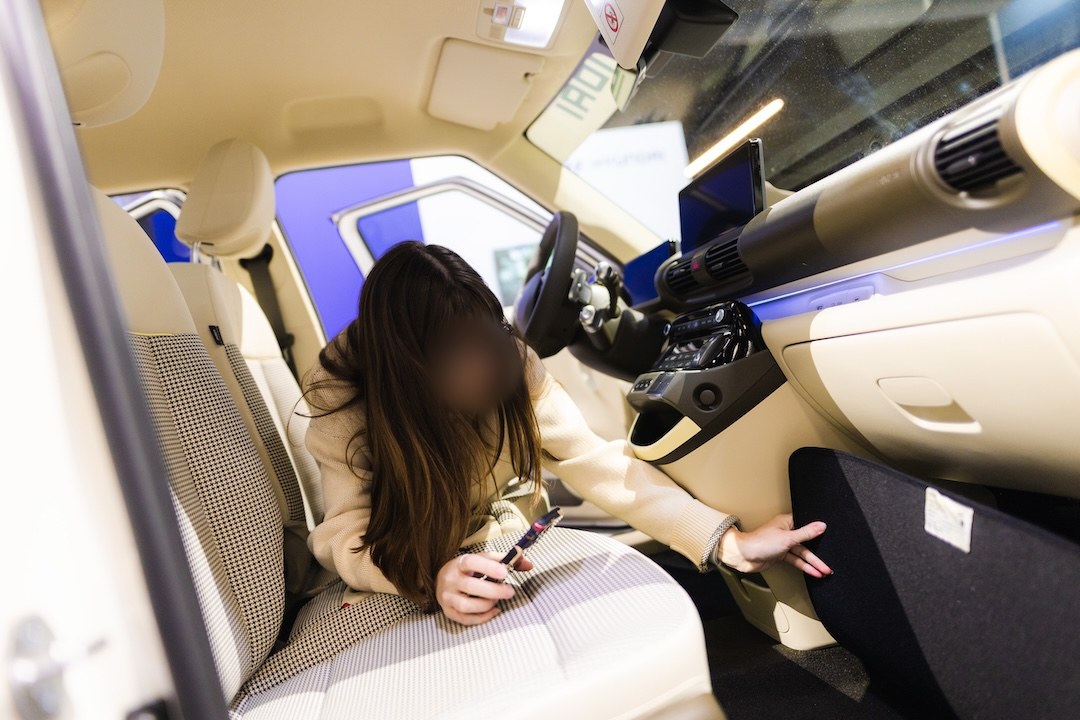 Une visiteuse cherche un QR code dans l'habitacle de la Hyundai Inster