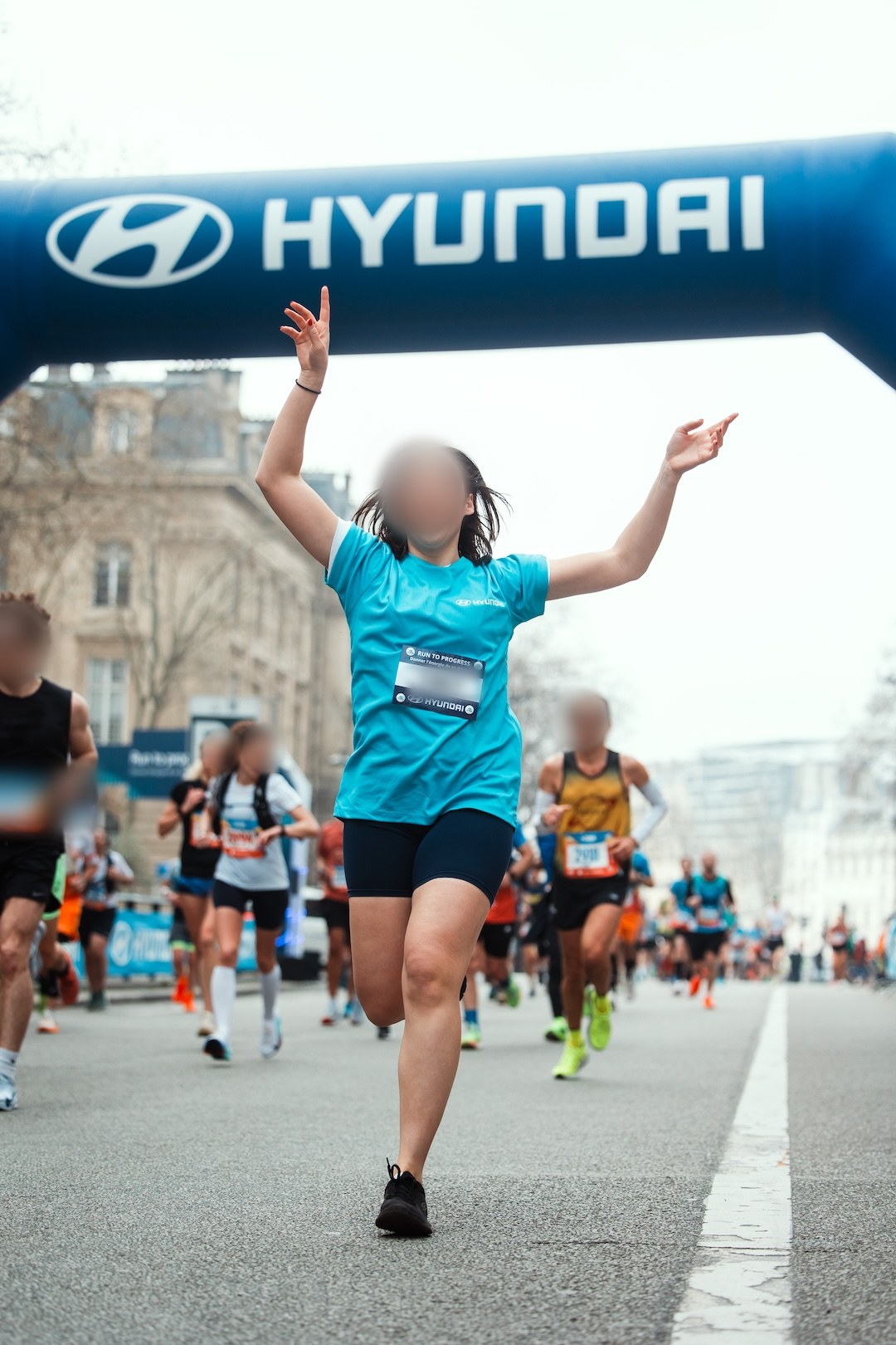 Une coureuse passe les bras levés sous l'arche Hyundai Run to Progress